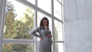 美丽的<strong>孕妇</strong>走在房子里，靠近一扇大窗户。 她穿着<strong>孕妇</strong>装. 美丽美丽